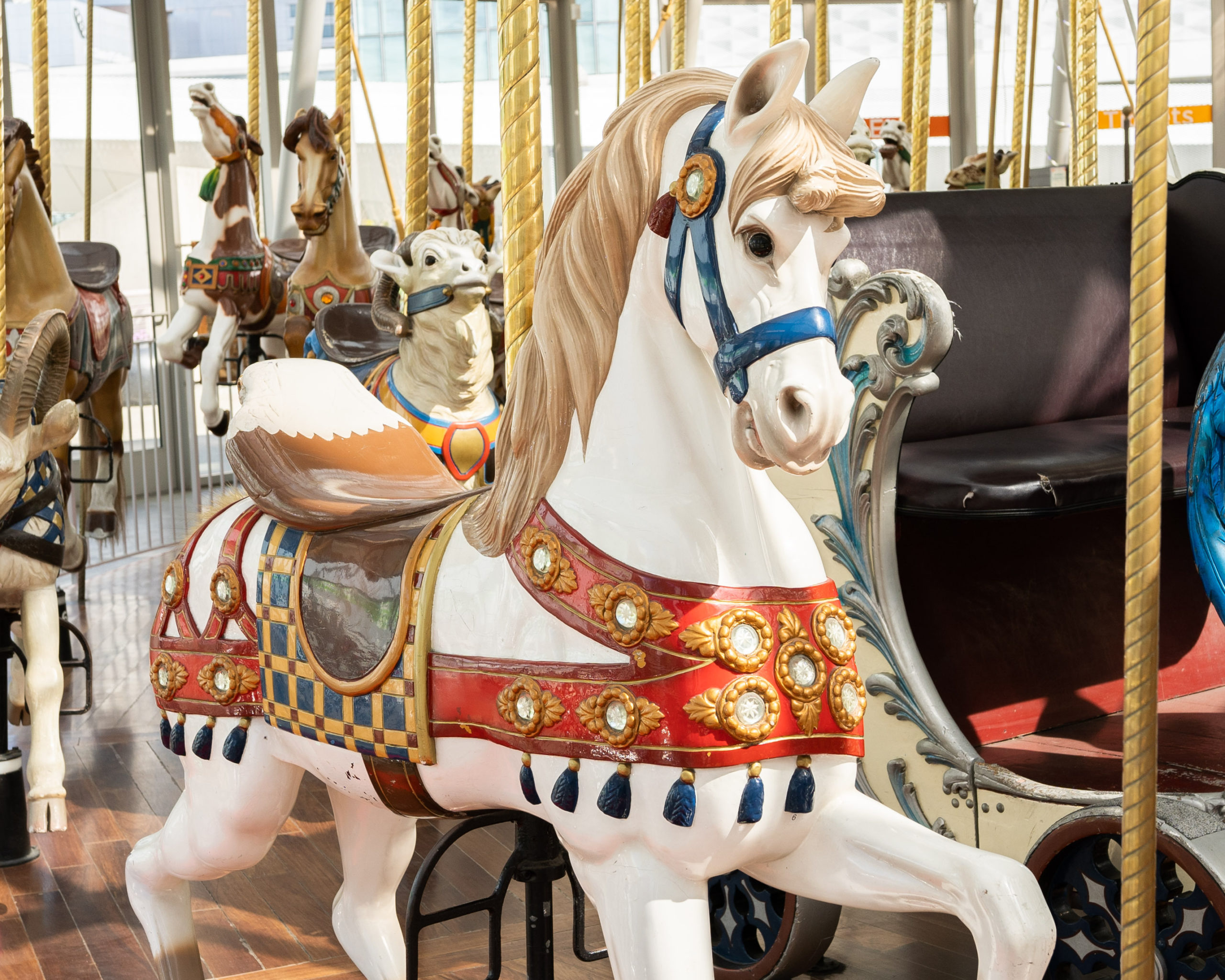 White horse carousel animal with wooden red sash and blue wooden bridle